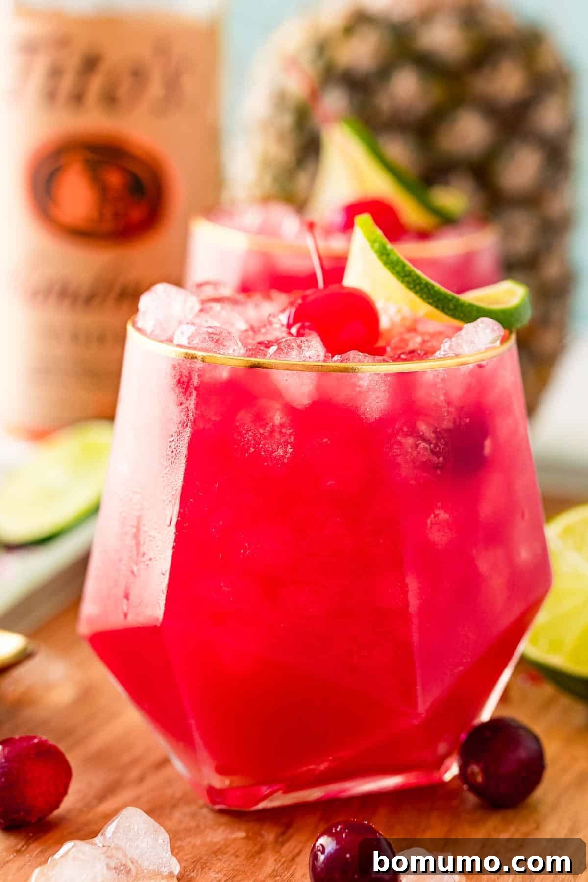 A vibrant red Bay Breeze cocktail featuring vodka, cranberry, and pineapple juice, with fresh pineapple in the background.