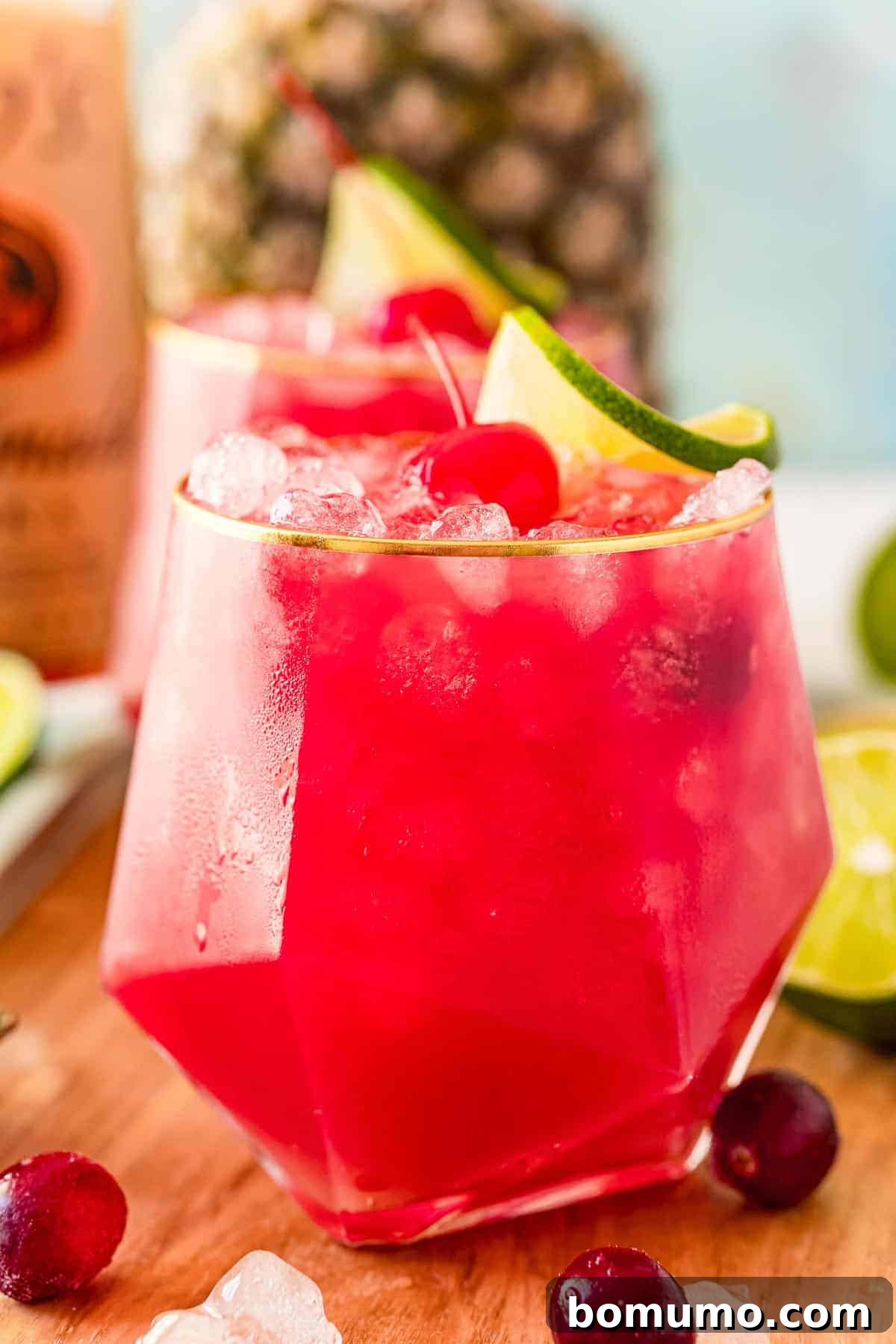 A close-up of a Bay Breeze cocktail, elegantly garnished with a lime slice and a maraschino cherry.