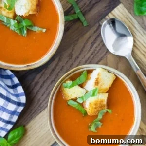 Overhead view of three small bowls of instant pot tomato soup, topped with croutons and fresh basil.