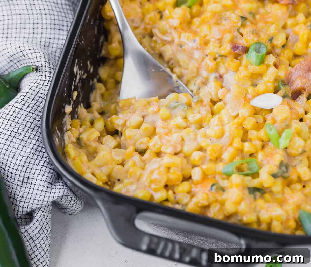 Close up of a casserole made with corn, bacon, and peppers, being scooped out with a spoon.