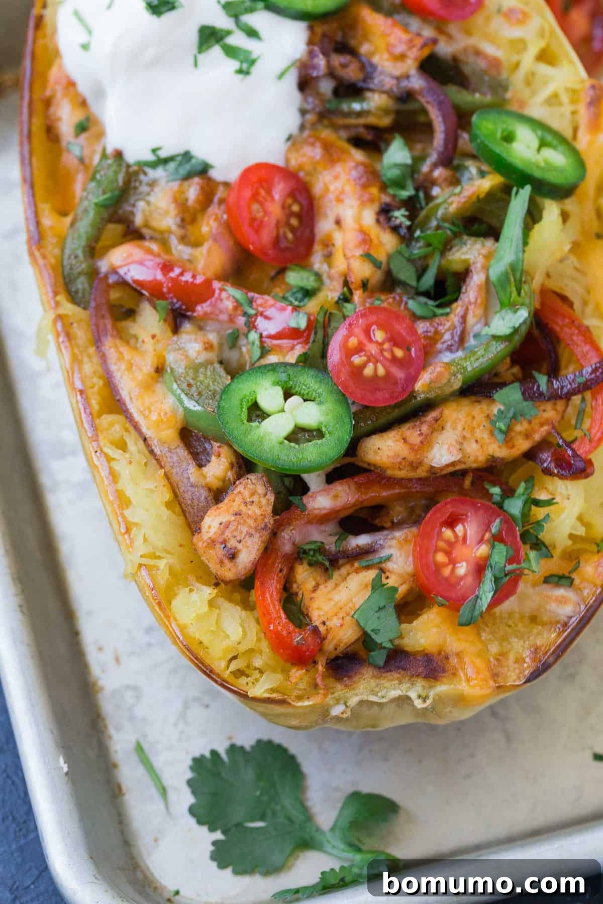 Close-up view of a vibrant chicken fajita stuffed spaghetti squash half, revealing the perfectly cooked chicken, colorful bell peppers, and melted cheese, ready to be served.