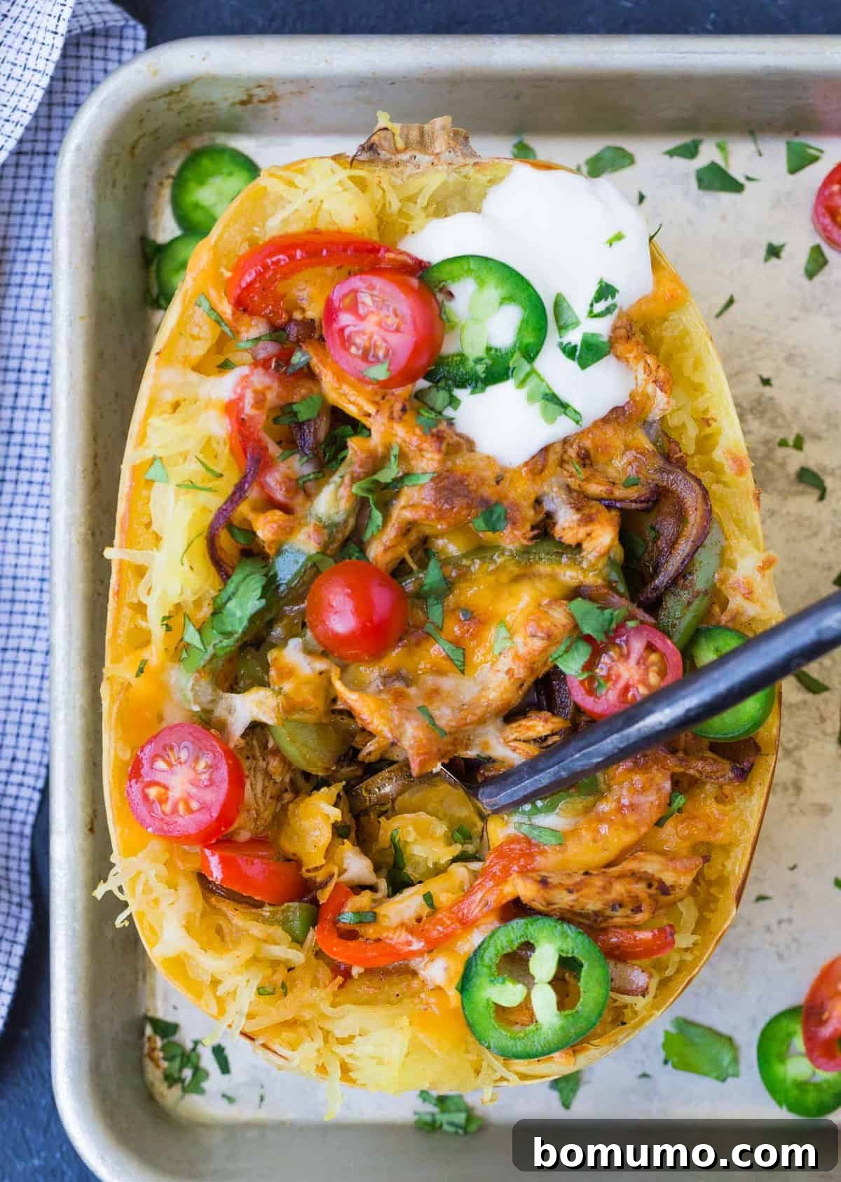 A fork is gently stuck into a beautifully prepared chicken fajita stuffed spaghetti squash, showcasing the rich filling and inviting texture, ready to be enjoyed.