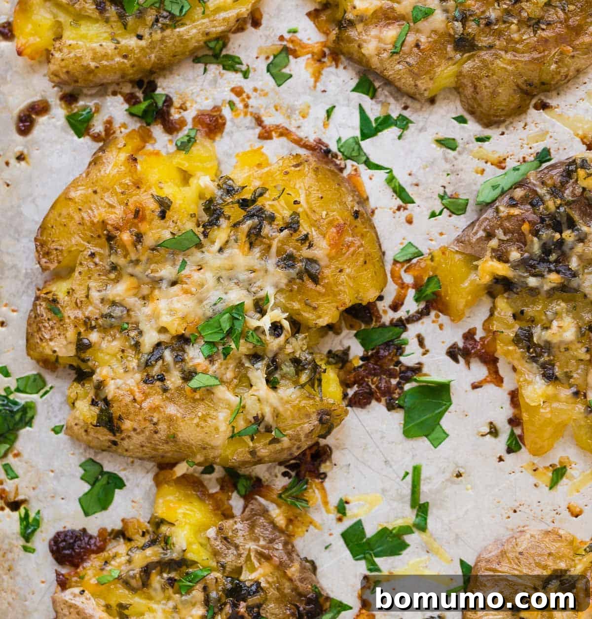Close up overhead view of a smashed potato with garlic butter, parmesan, and parsley.