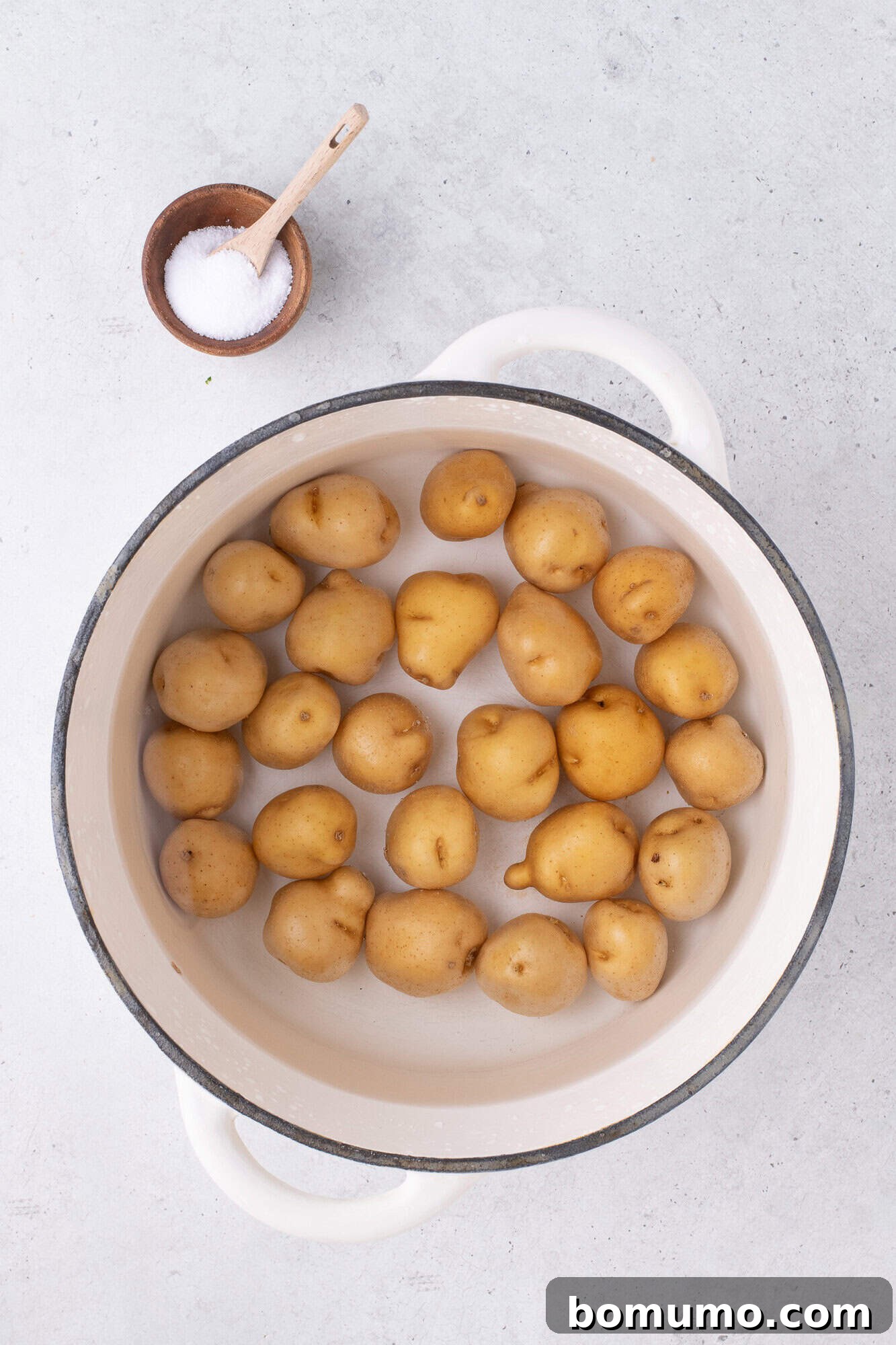 Baby potatoes being boiled in a large pot.