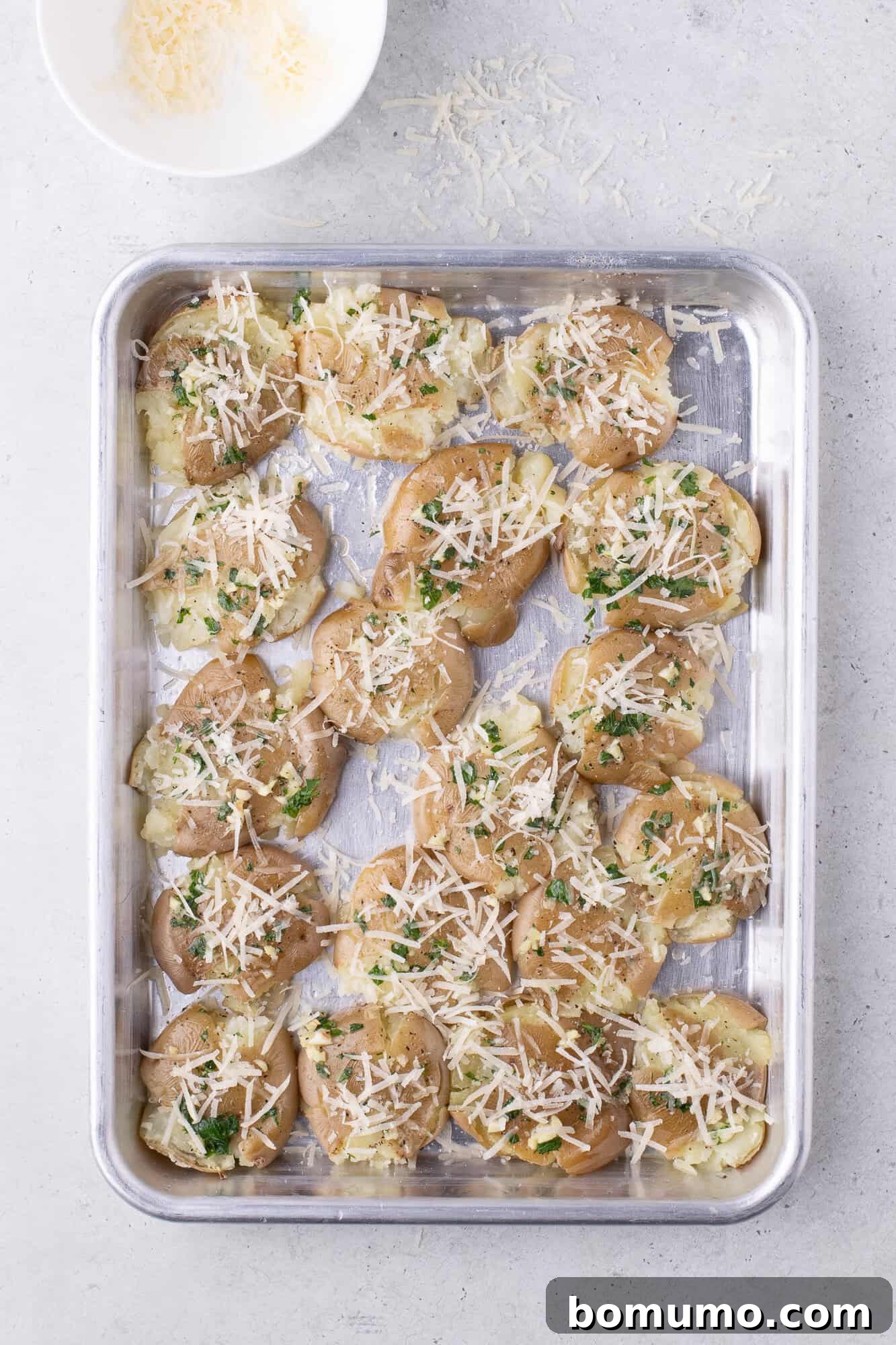 Cheese sprinkled on smashed potatoes.
