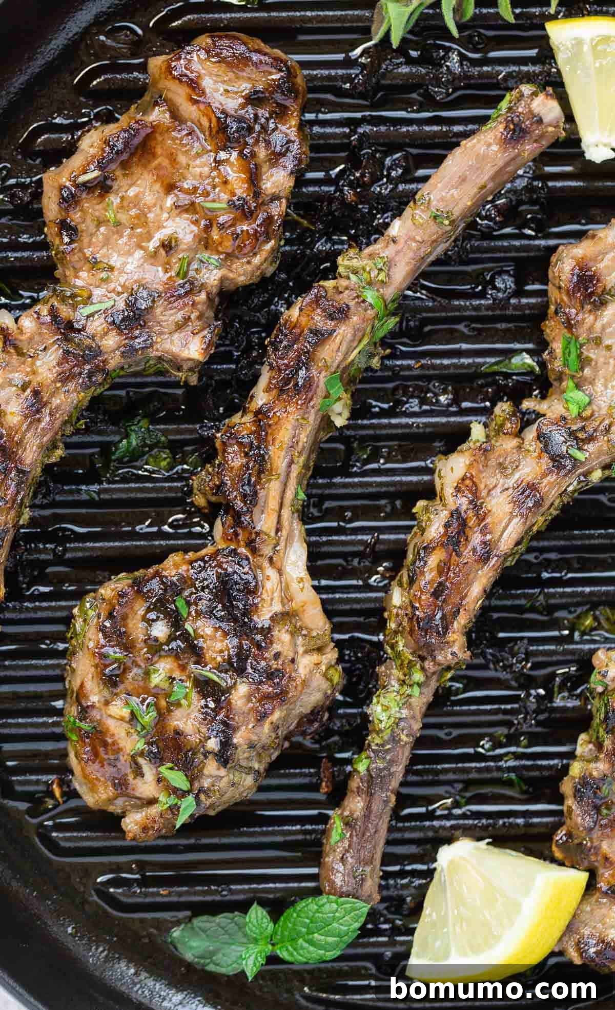 Aromatic Garlic Herb Lamb Chops 2 Exquisitely grilled lamb chops adorned with fresh herbs and vibrant lemon wedges, ready to be served.