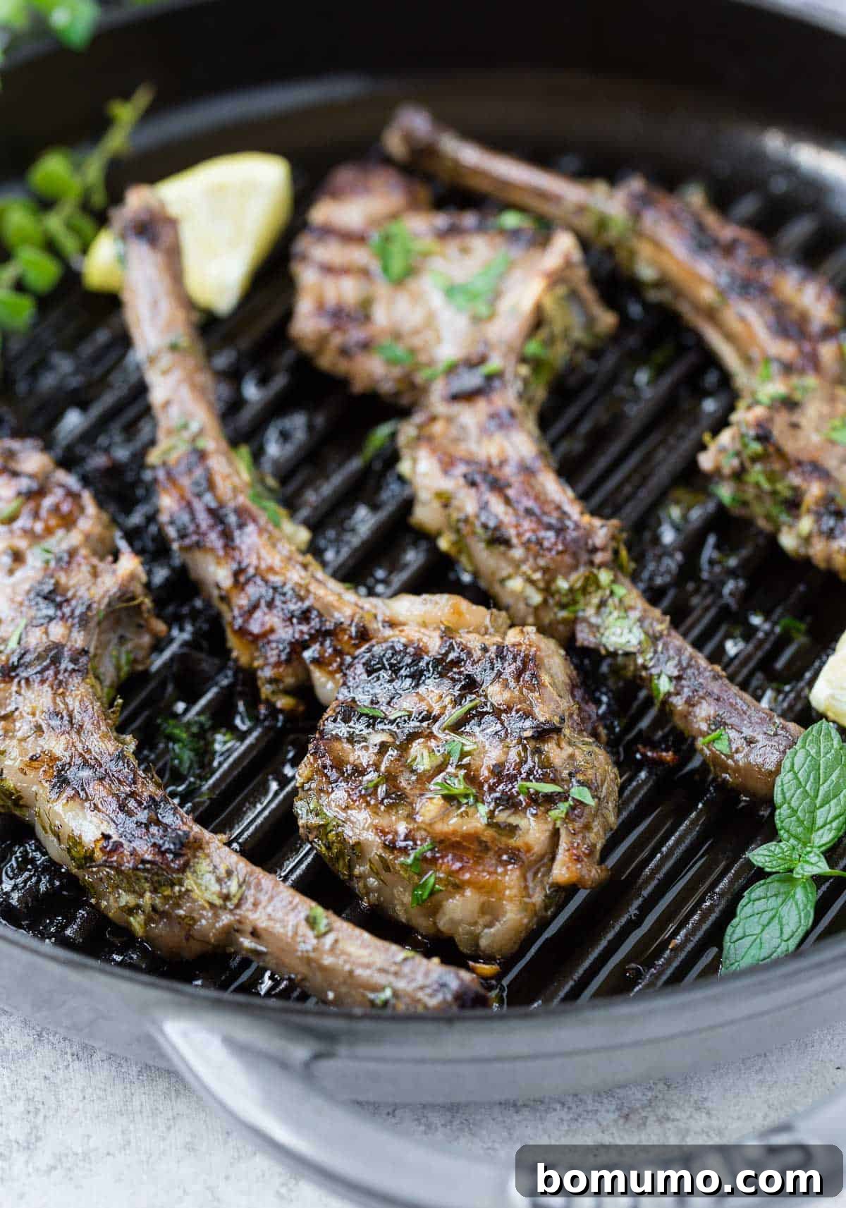 Aromatic Garlic Herb Lamb Chops 7 A beautifully plated dish of cooked lamb chops, garnished with fresh herbs and bright lemon slices.