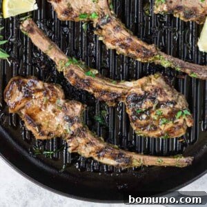Lamb chops on a grill pan, sprinkled with fresh herbs.