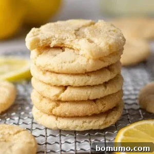 Lemon cookies in stack, the top one with a bite taken out of it.