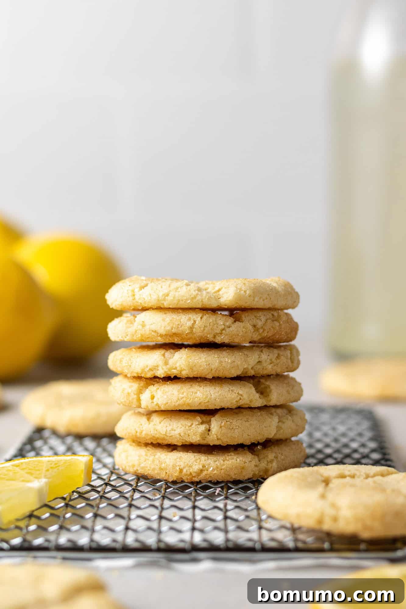 Lemon sugar cookies in a tall stack on wiring baking rack.