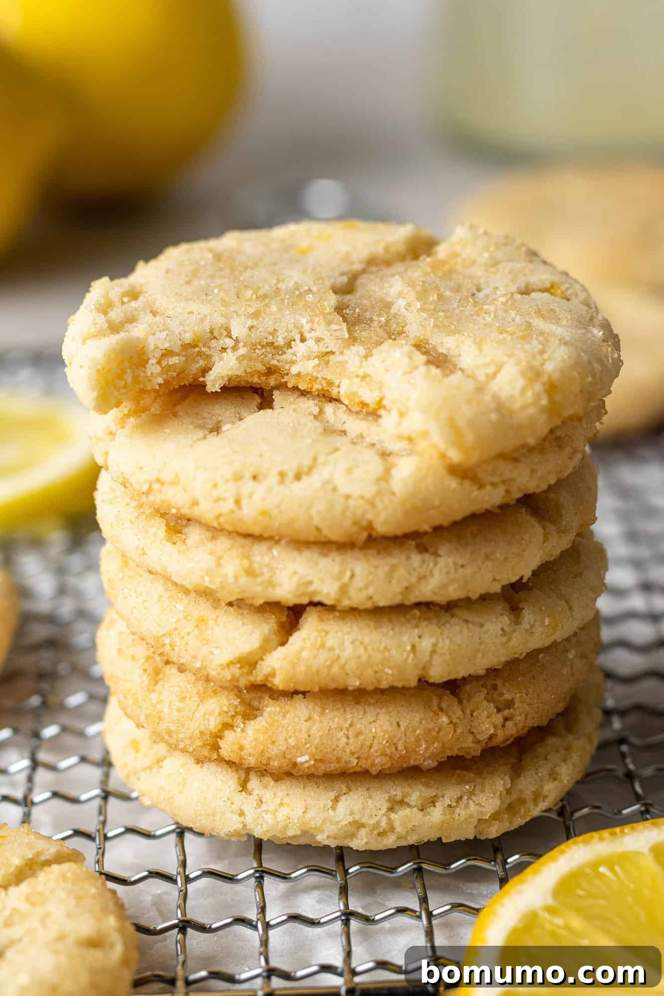 Lemon cookies in stack, the top one with a bite taken out of it.