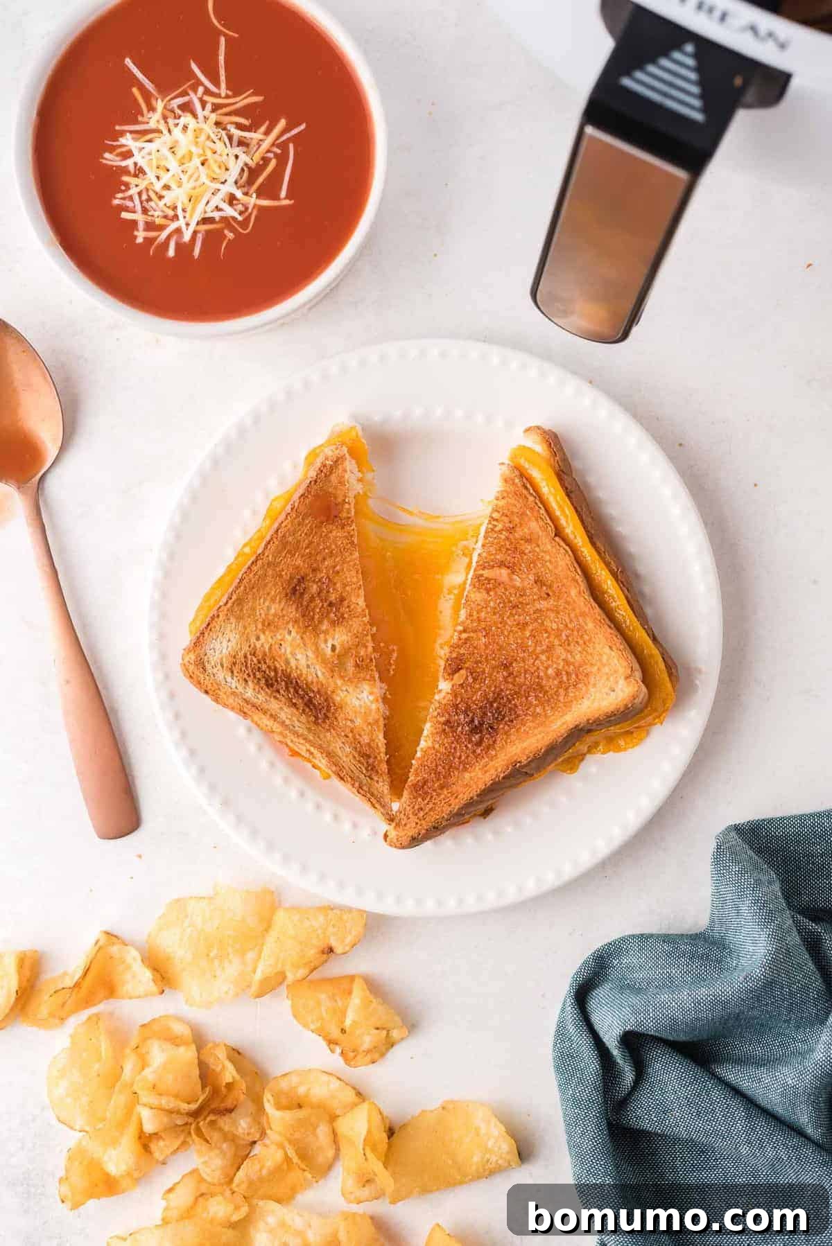 Overhead view of a grilled cheese sandwich on a white plate, being pulled apart to show cheese.
