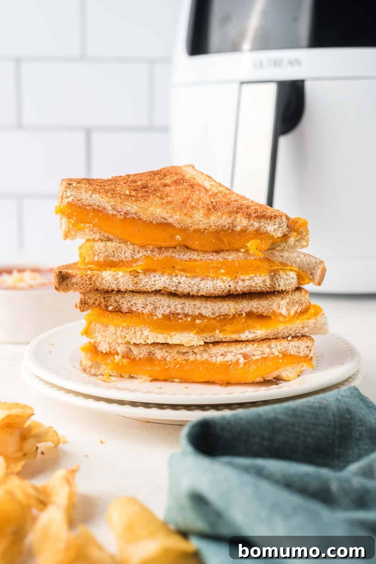 Stack of super cheese grilled cheese sandwich halves, with an air fryer in the background.