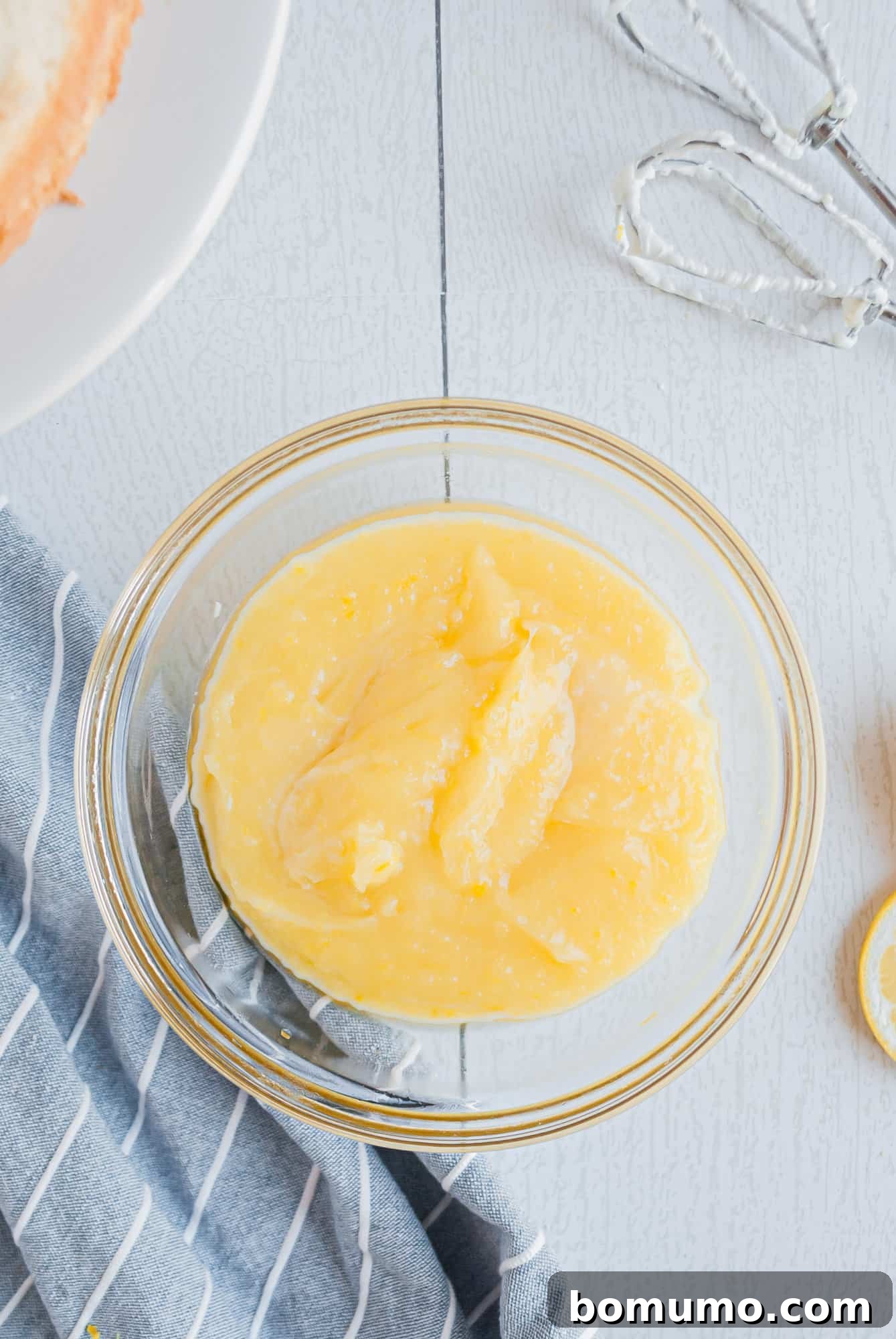 A small bowl filled with golden, smooth lemon cake filling, showcasing its rich texture.