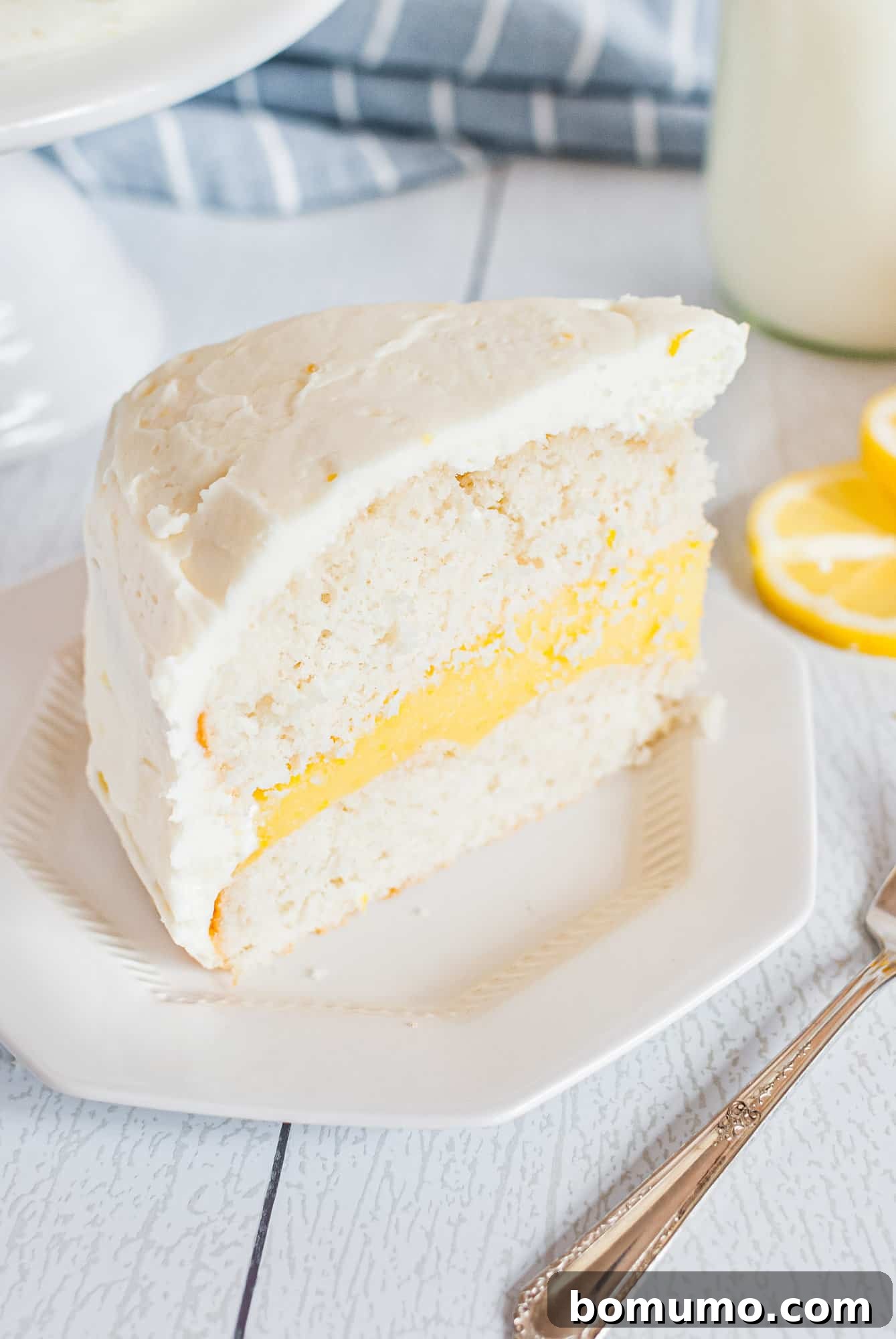 A pristine slice of lemon cake rests on a white plate, inviting a taste.