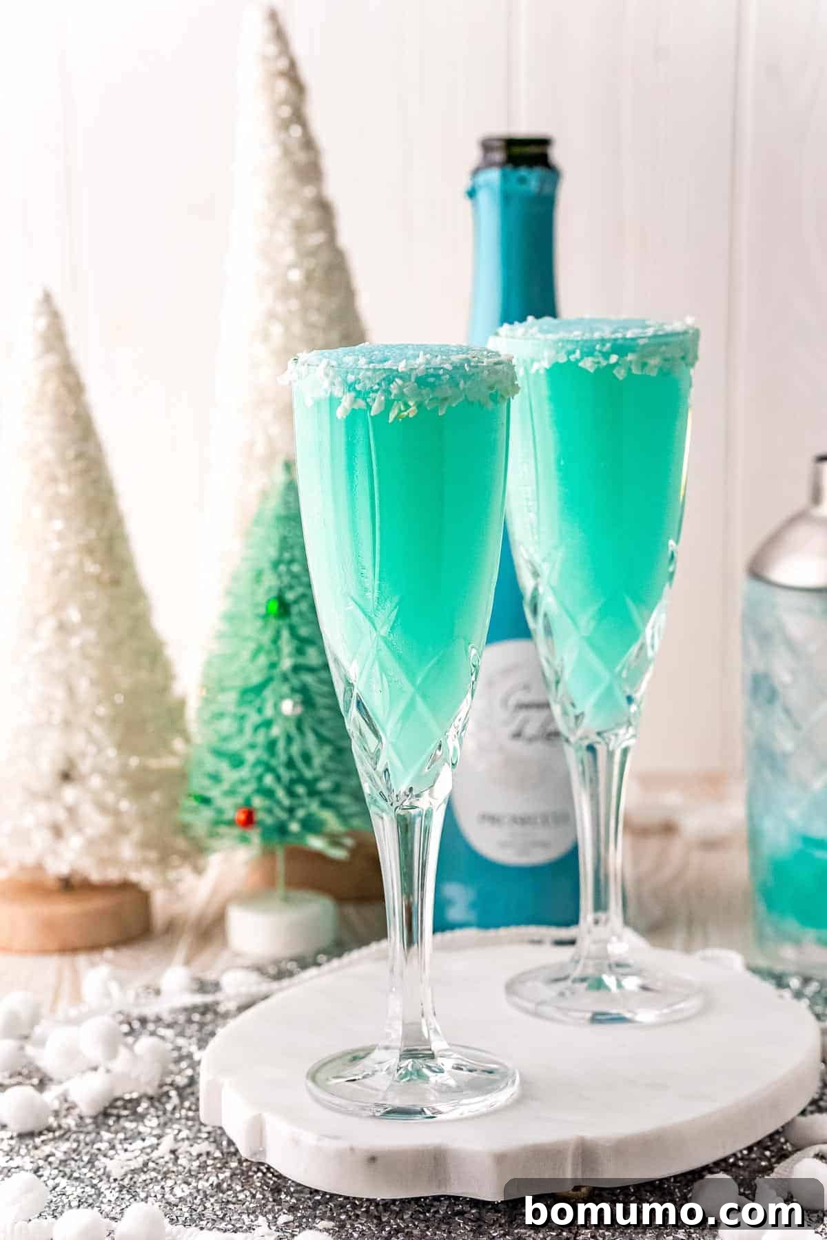 Two bright blue mimosas with a festive winter background, perfect for holiday gatherings.