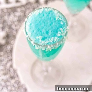 A bright blue mimosa with a coconut rim in a champagne glass, capturing the essence of winter.