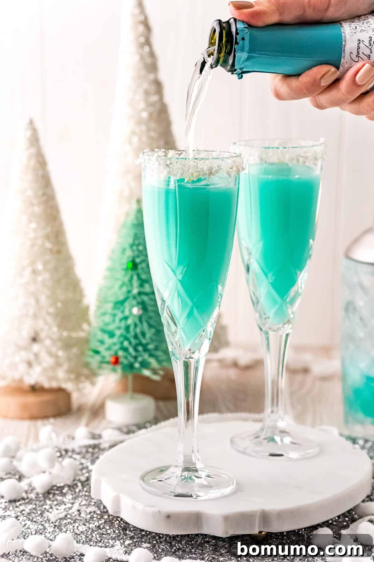 Prosecco being poured into a vibrant blue cocktail, adding a festive sparkle.