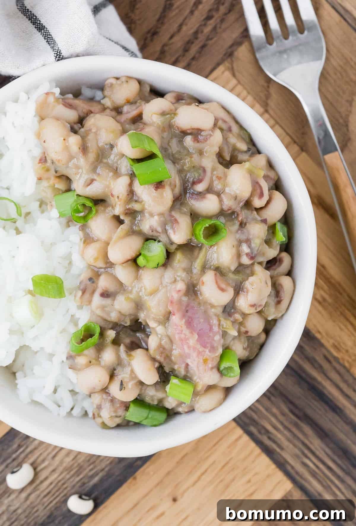 Close up view of stewed black eyed peas, white rice, and green onions.