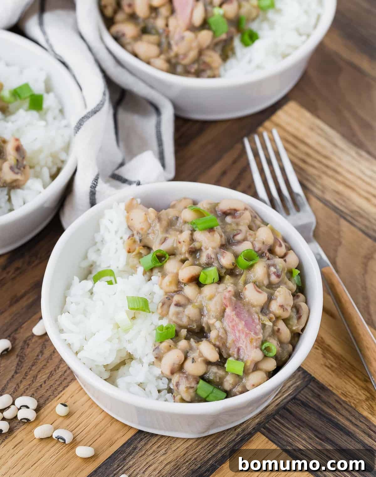 Black eyed peas and rice in a white bowl on a wooden background.
