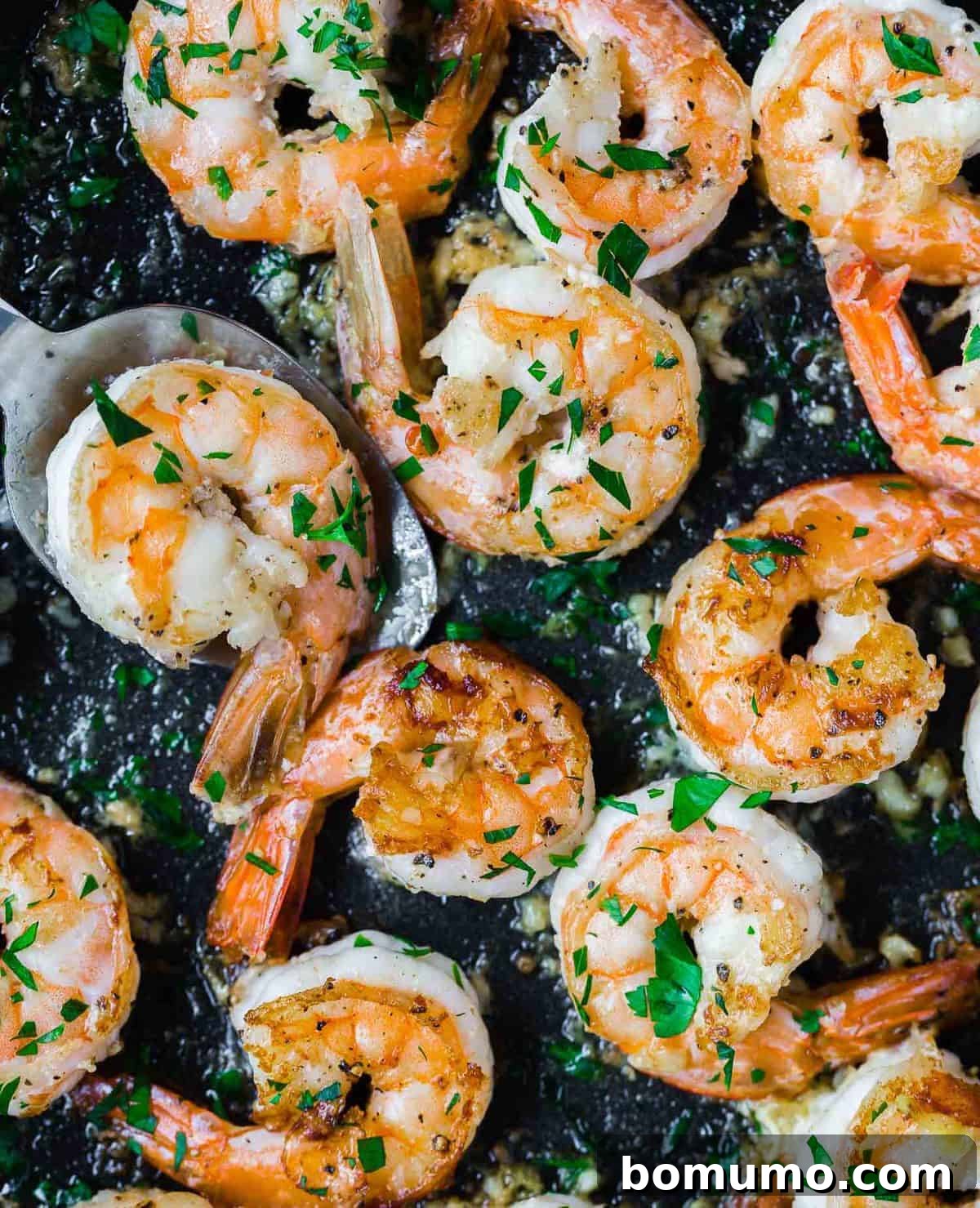 Effortless Lemon Pepper Shrimp 4 Close-up of succulent cooked lemon pepper shrimp nestled in a black skillet, ready for serving.