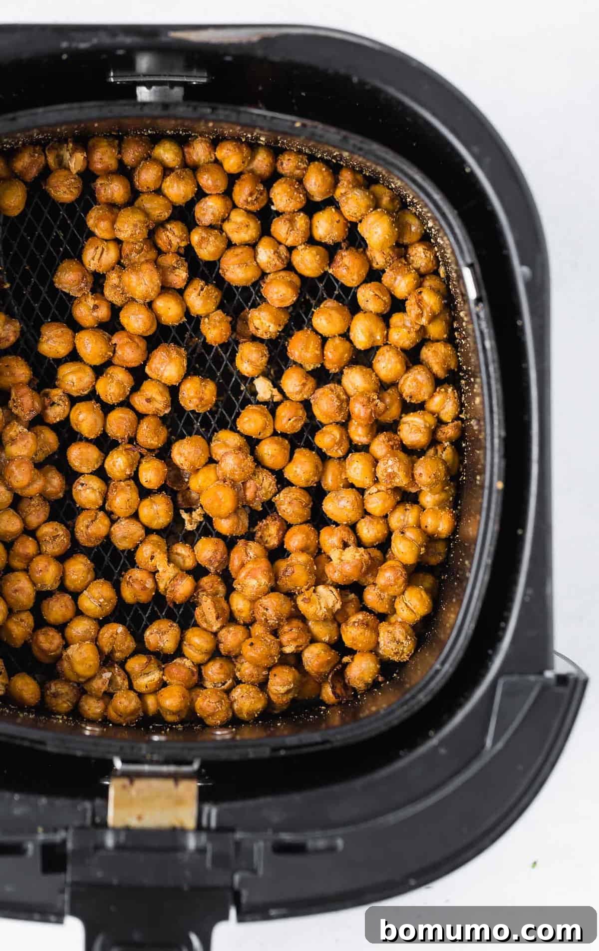 Overhead view of crispy chickpeas in a black air fryer basket.
