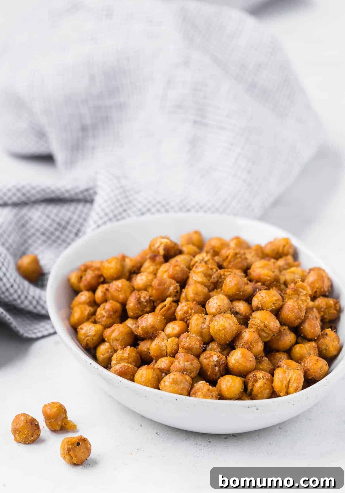 A bowl of chickpeas that have been air fried, black and white linen in background.