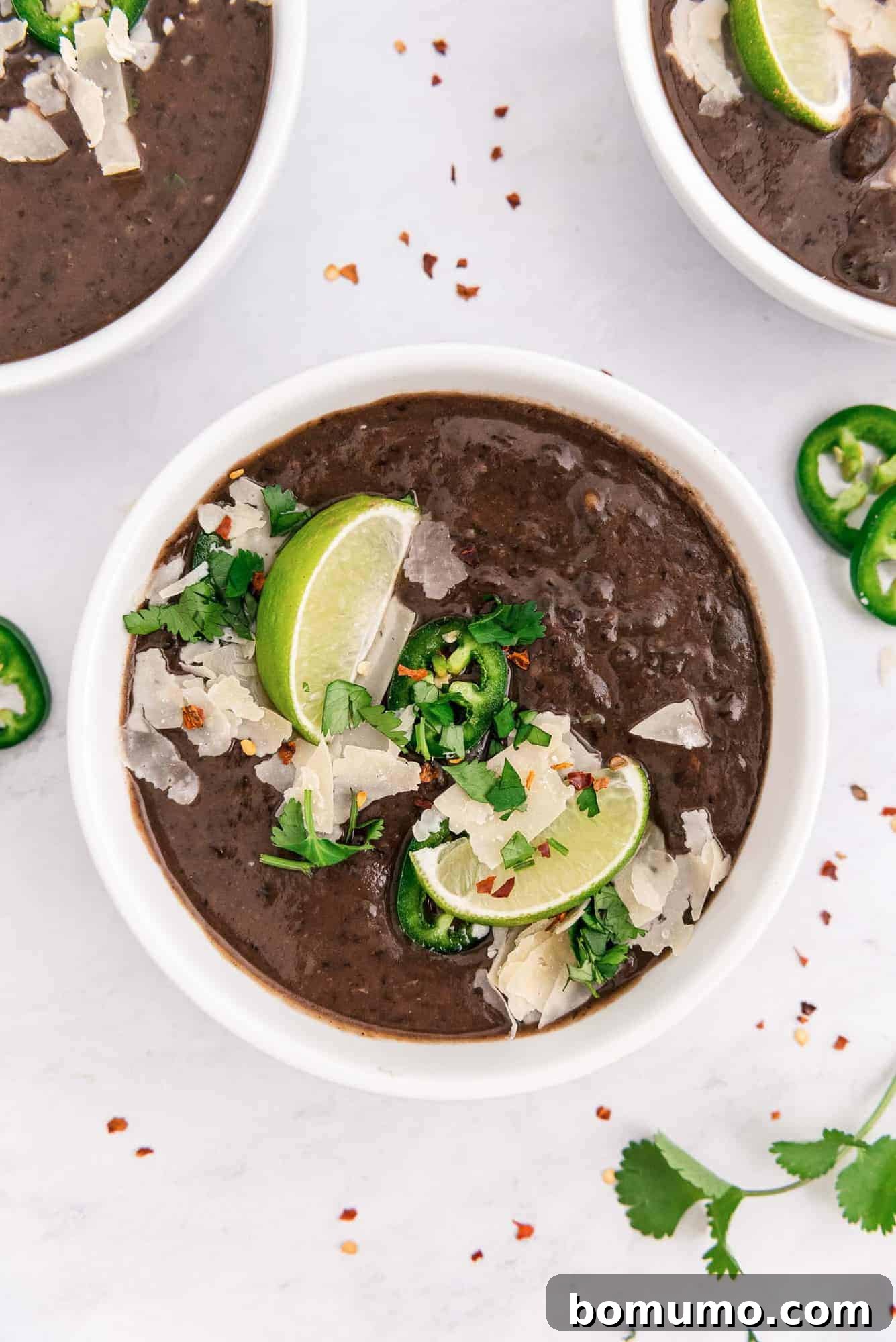 Overhead view of a comforting bowl of Instant Pot black bean soup, garnished with vibrant lime wedges and fresh cilantro.