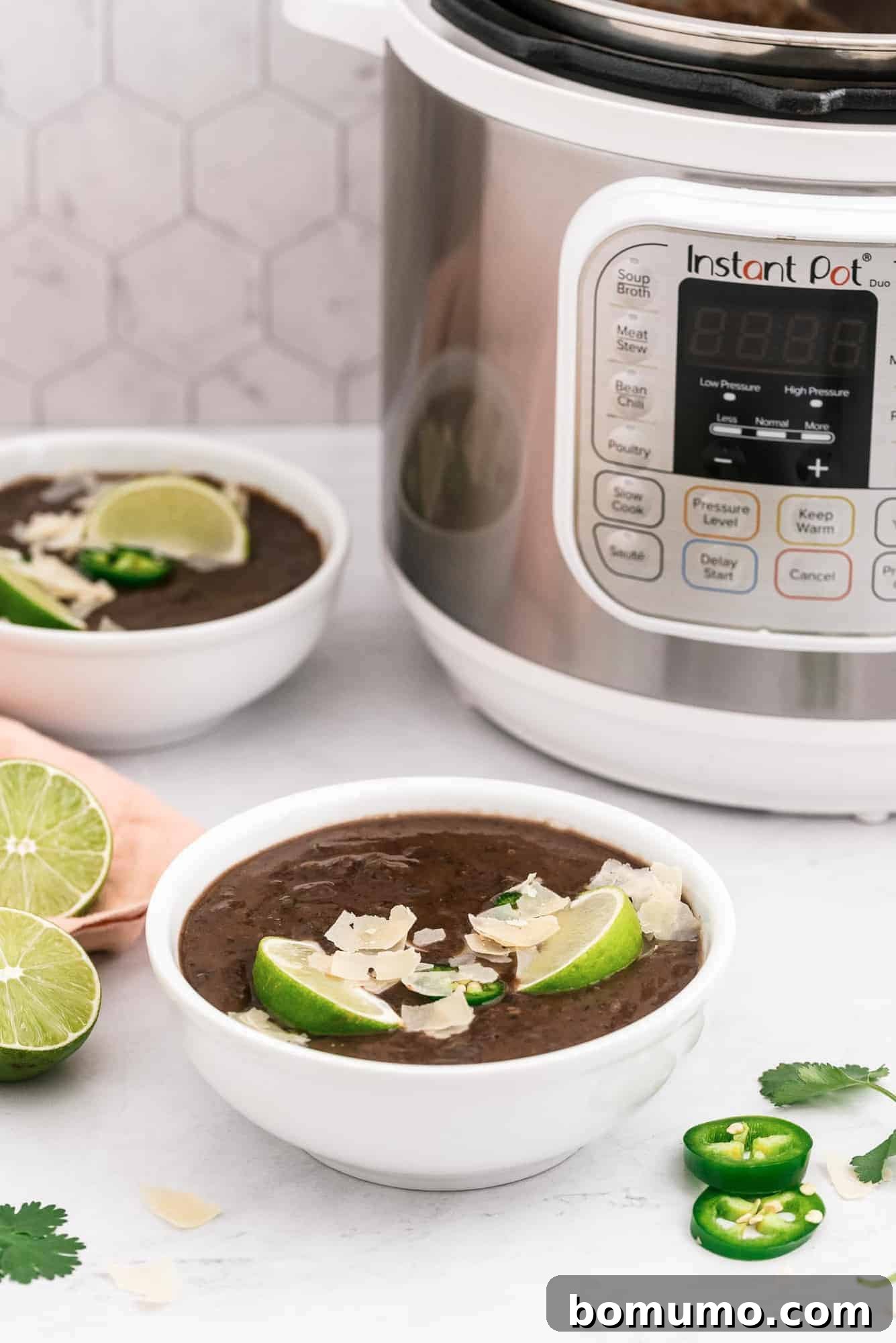 Two steaming bowls of Instant Pot black bean soup, beautifully presented in front of an Instant Pot appliance.