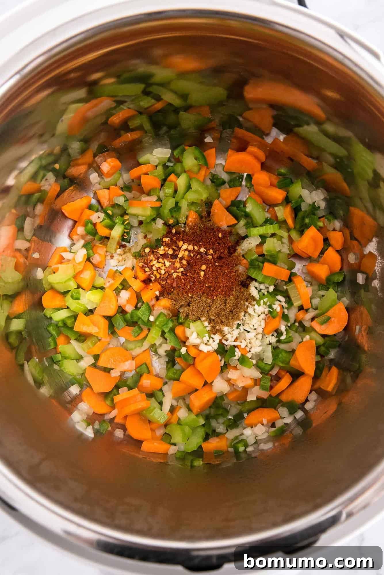 Close-up view of vibrant sautéed vegetables and aromatic spices in an Instant Pot, forming the delicious base for black bean soup.