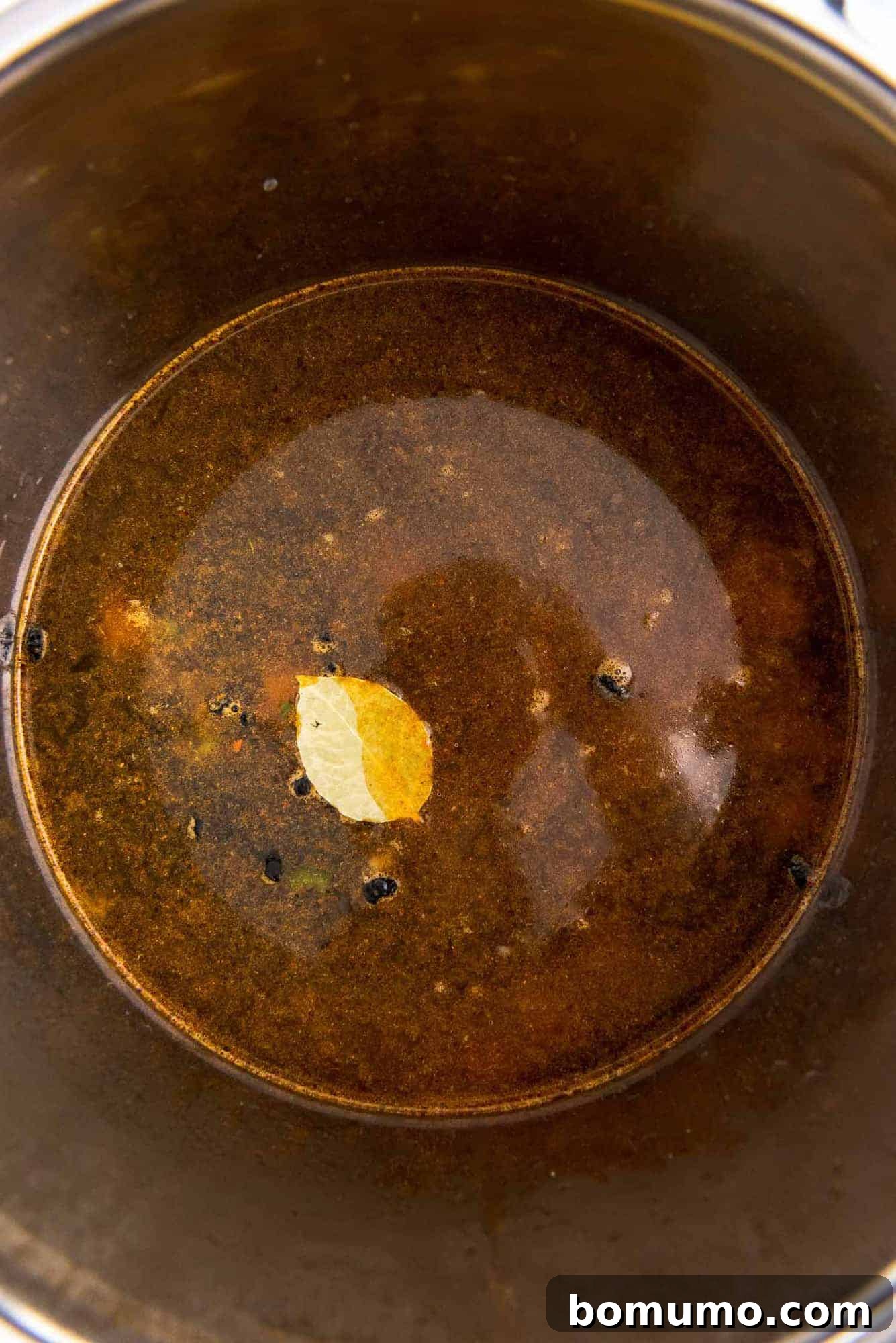 Overhead view of the black bean soup ingredients, including dry beans, broth, and spices, settled in the Instant Pot, ready for pressure cooking.