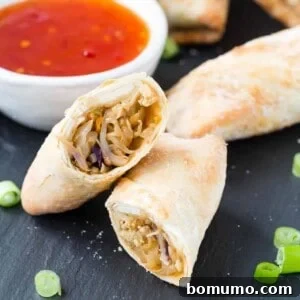 A cut-open egg roll on a black surface, with dipping sauce visible in the background.
