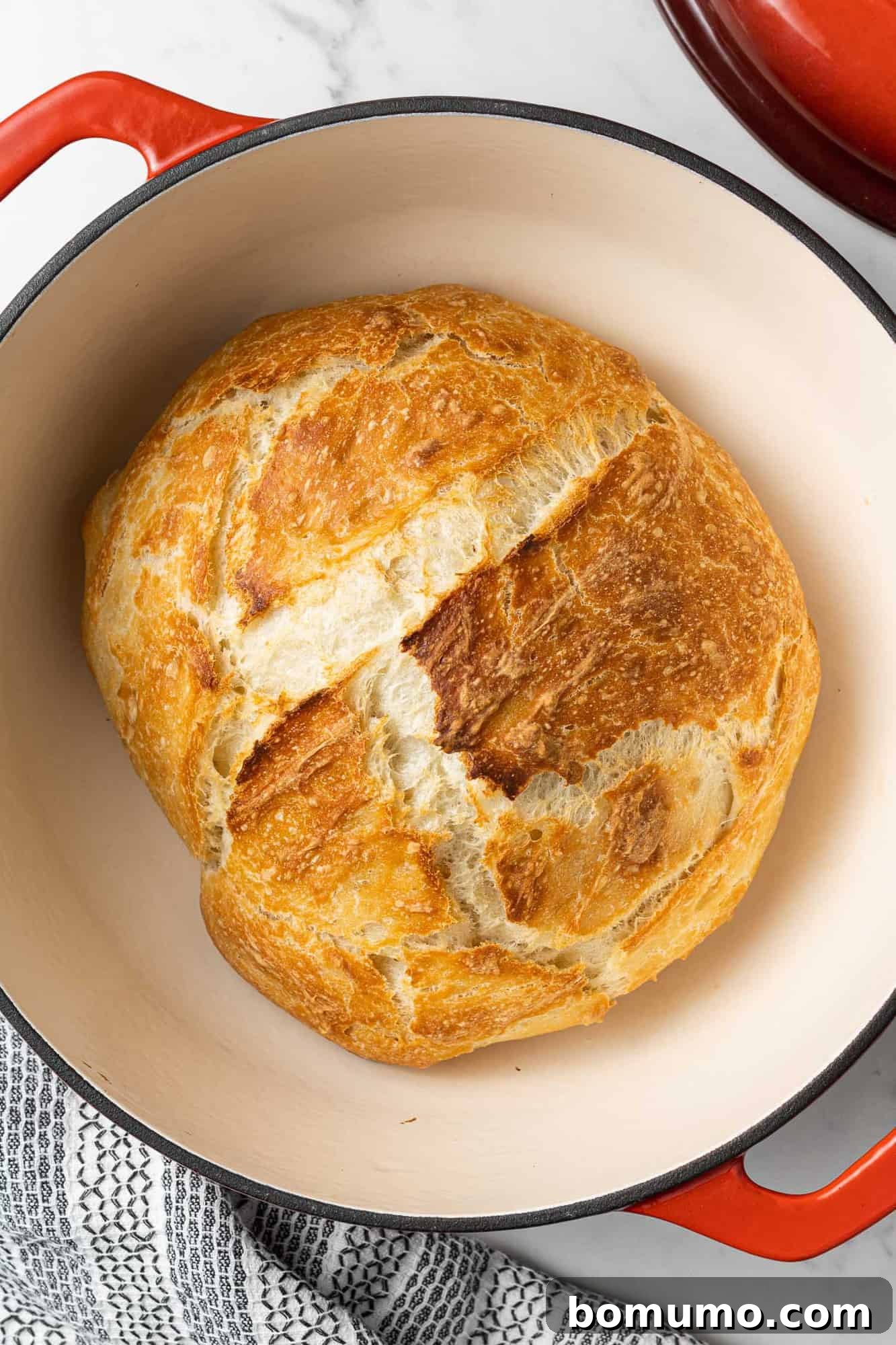 Overhead view of a perfectly baked, crusty loaf of Dutch oven bread, fresh out of the oven.