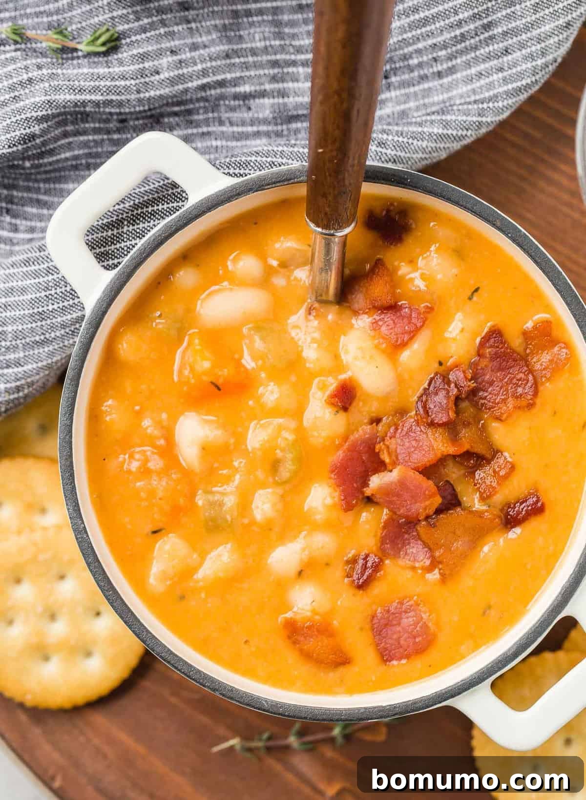 Versatile Bean and Bacon Soup 7 Overhead shot of a vibrant, orange-hued bowl of homemade bean soup, generously topped with crumbles of crispy bacon, highlighting its rich texture and appetizing presentation.