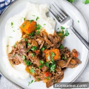 Overhead view of Italian pot roast on a plate, served over mashed potatoes.