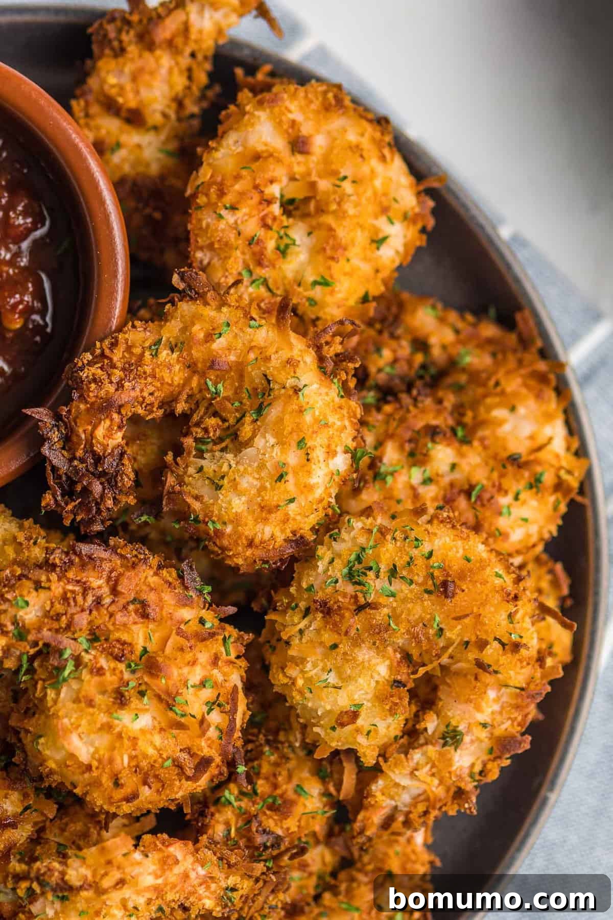 A close-up, high-angle view of a generous pile of golden brown, crispy air fryer coconut shrimp, ready to be enjoyed.