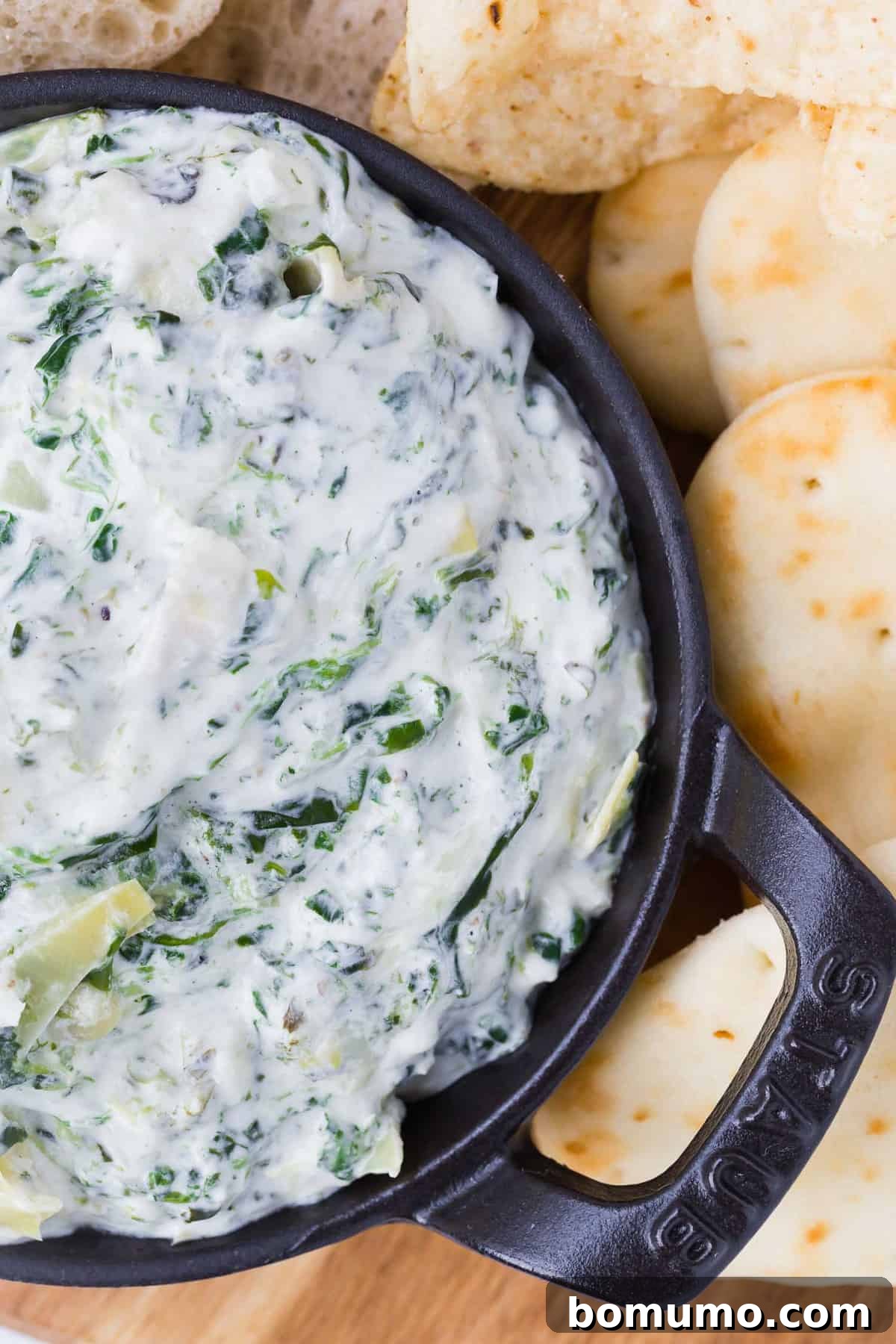 A close-up, appetizing view of a creamy and rich spinach artichoke dip, revealing its luscious texture, melted cheese, and tender pieces of spinach and artichoke.
