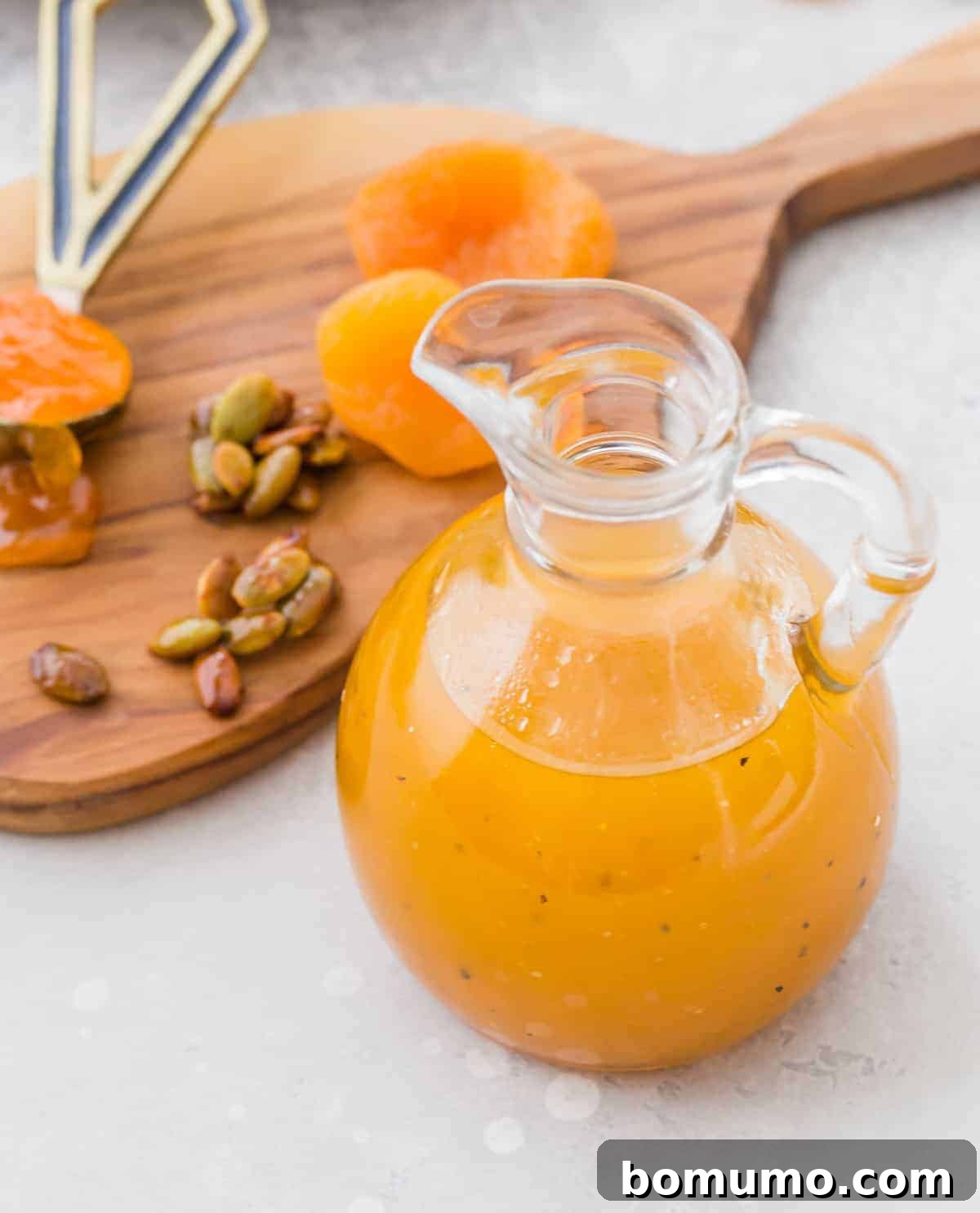 Dressing in a glass bottle, apricots and pepitas in the background.