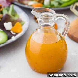 Bright orange salad dressing in a jar in front of salads.