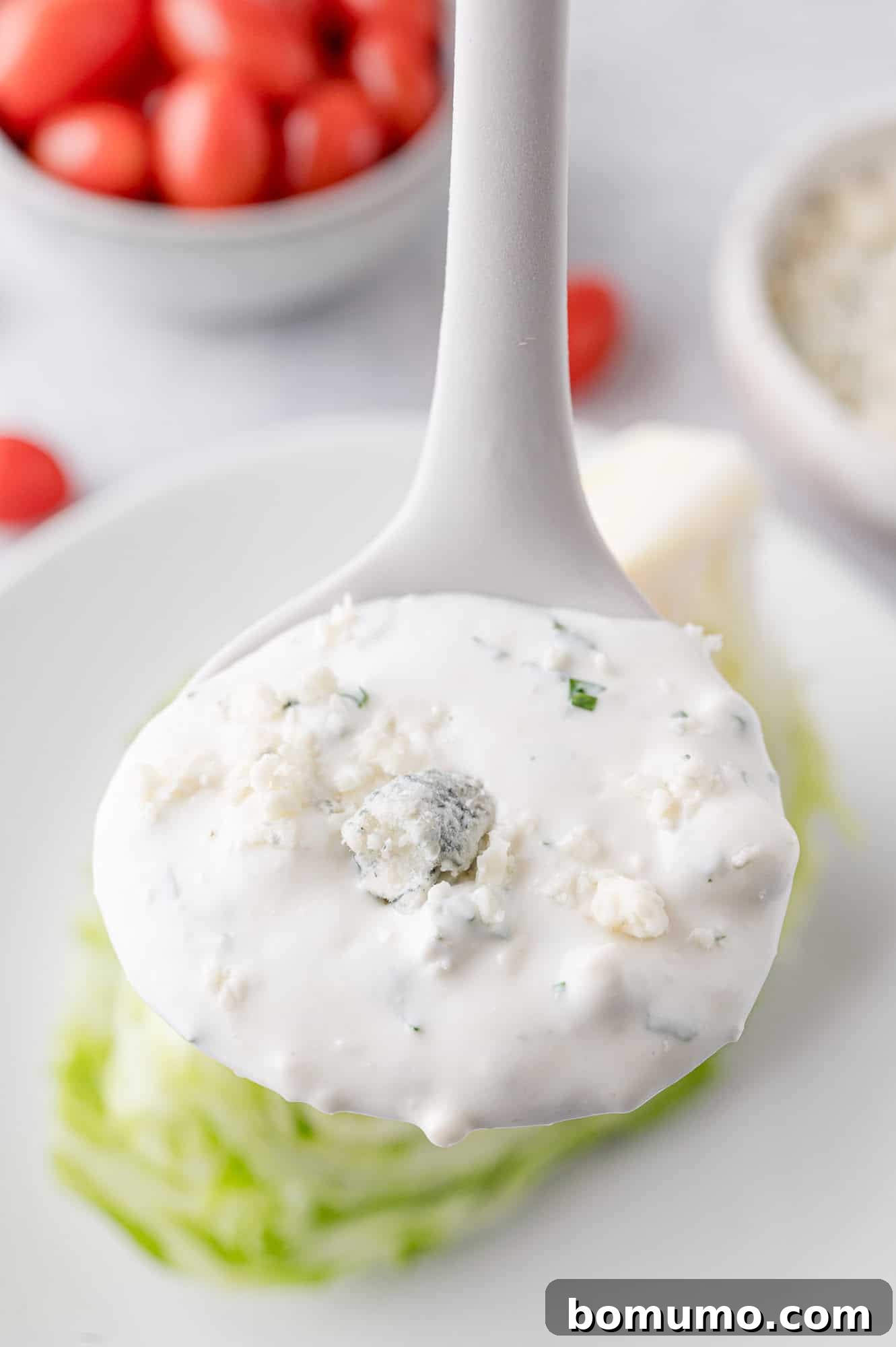 Creamy homemade blue cheese dressing elegantly presented on a small white ladle.