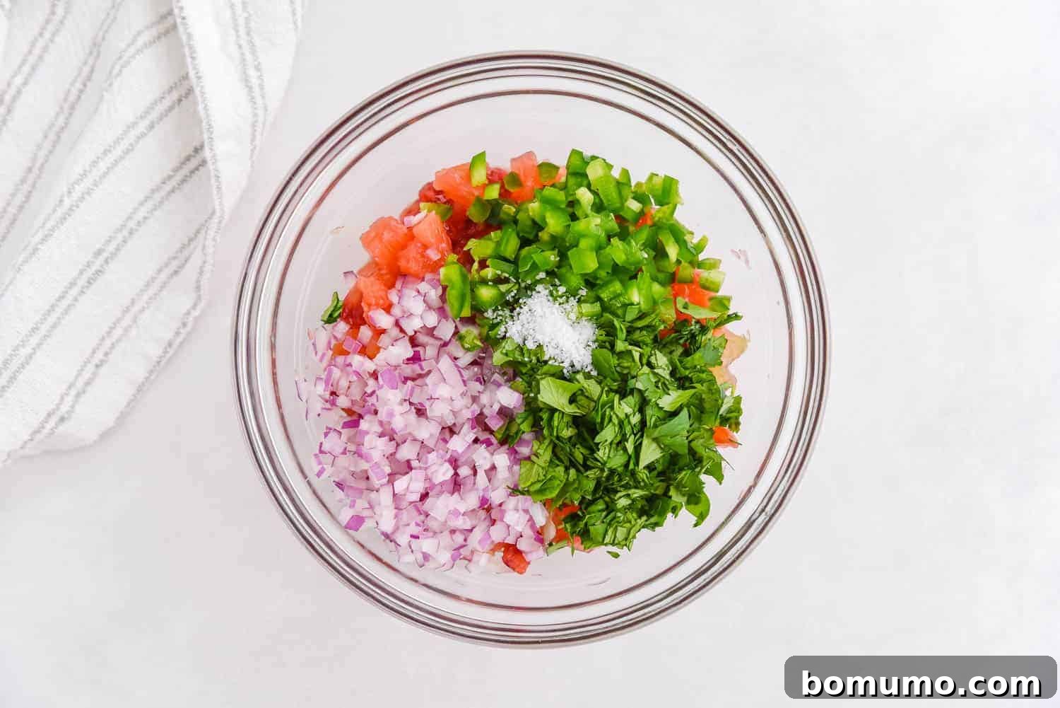 Unmixed salsa ingredients in a glass mixing bowl, showcasing vibrant citrus segments, red onion, and cilantro before stirring.