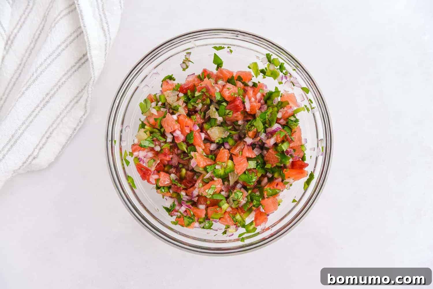 Fresh citrus salsa, with grapefruit, oranges, and lime, perfectly mixed together in a clear glass mixing bowl, ready for serving.