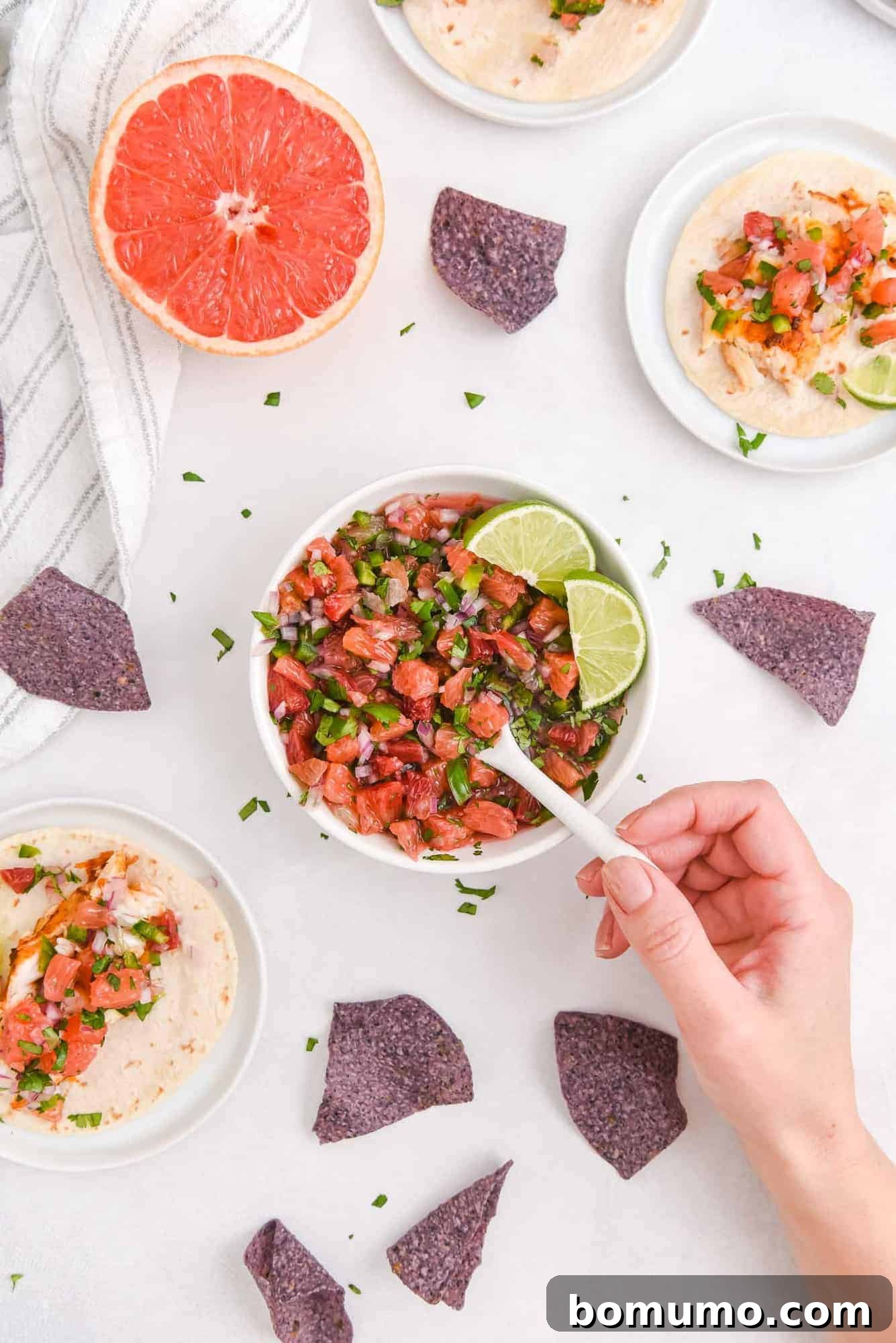 A spoon scooping a generous portion of fresh citrus salsa from a bowl, highlighting its vibrant colors and juicy texture.
