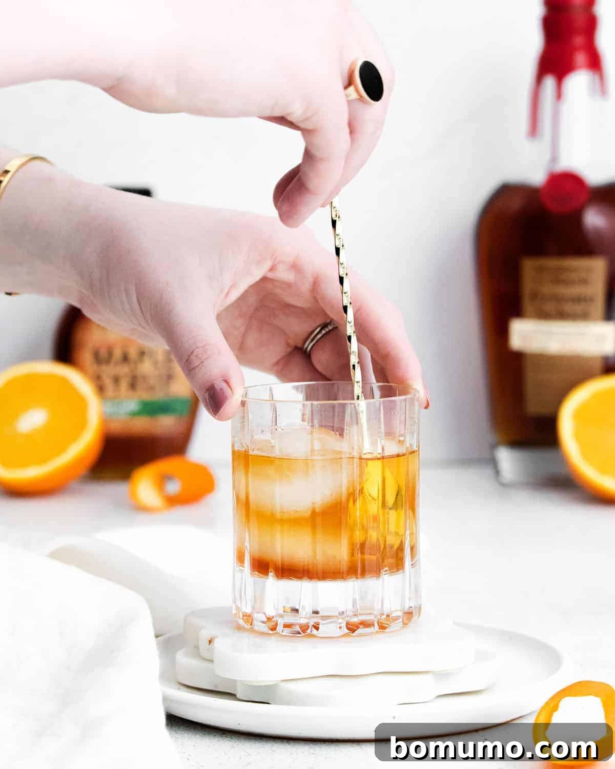 A close-up shot of a cocktail being gently stirred in a glass with a bar spoon, ensuring all ingredients are perfectly integrated and chilled.