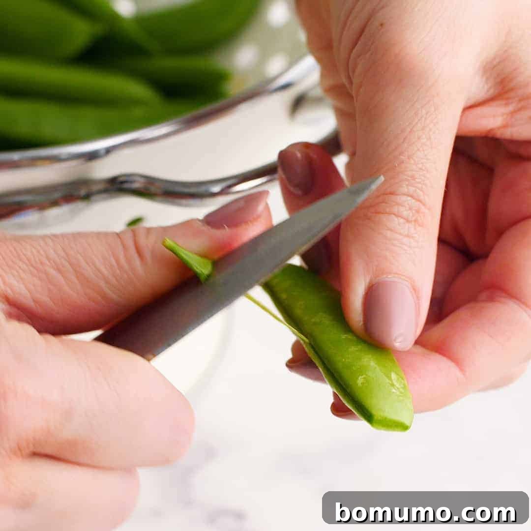 String being removed from a sugar snap pea.