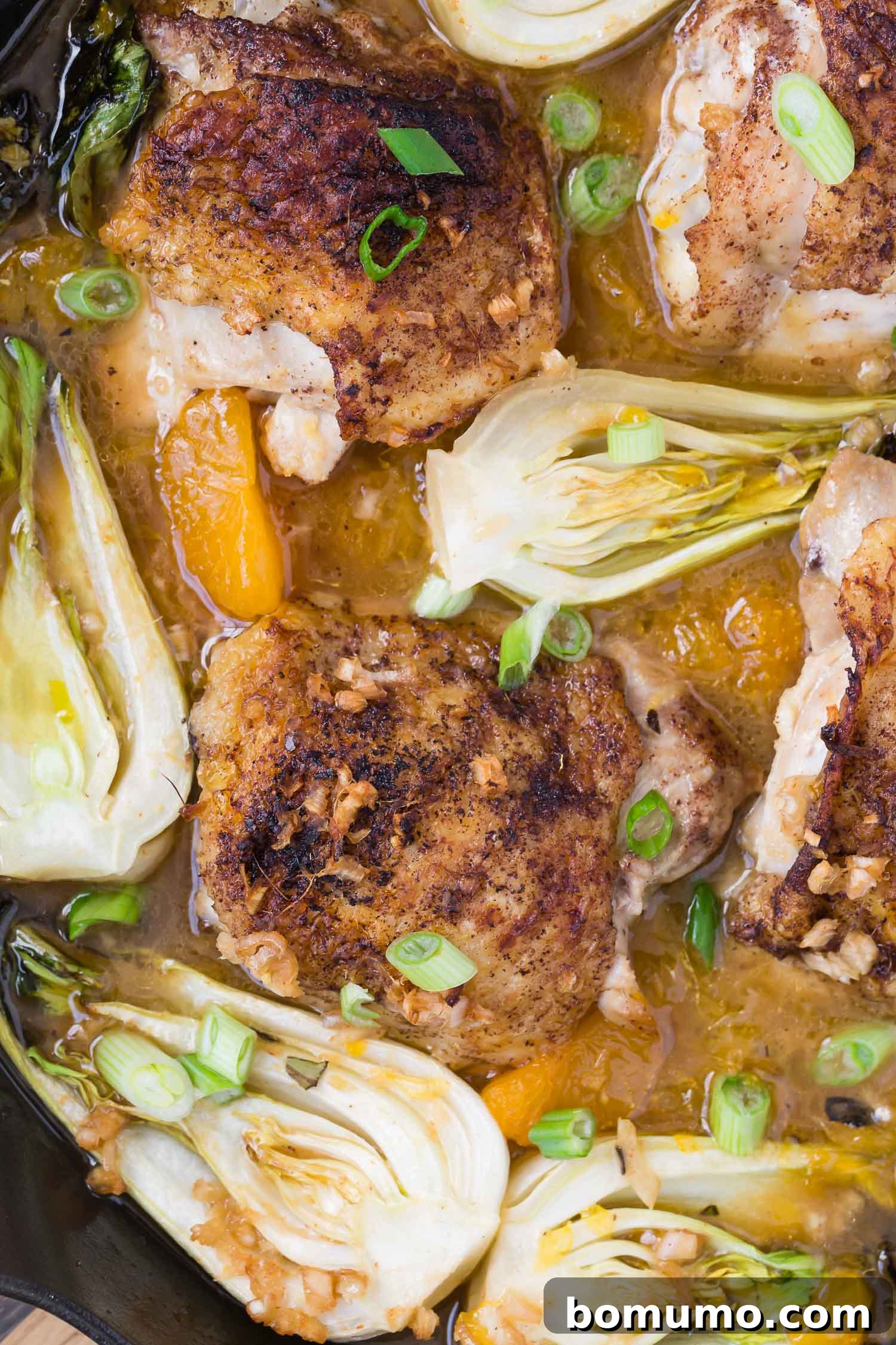 Close up of chicken and bok choy in a pan.