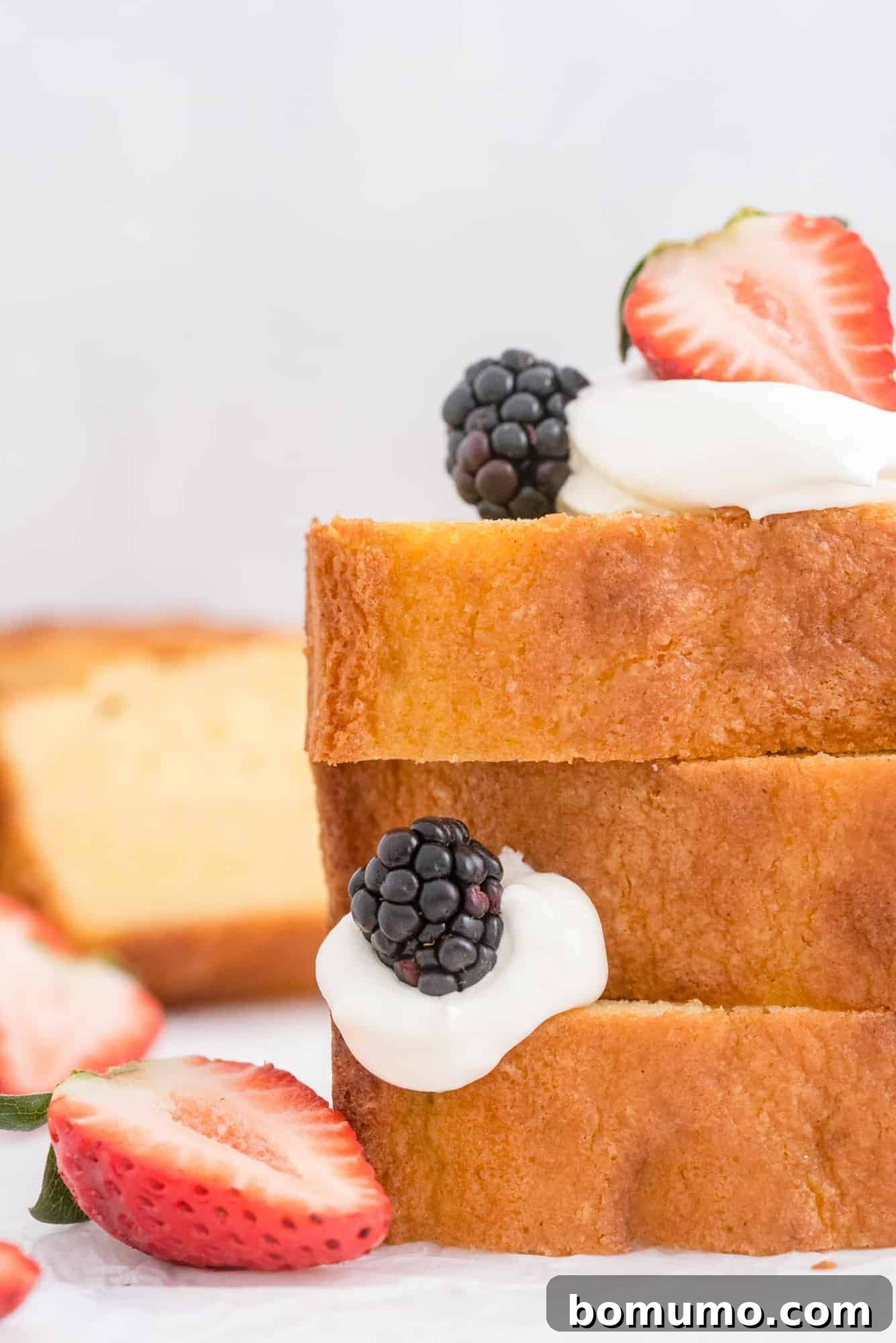 Timeless Pound Cake Perfection 12 Luxurious stack of pound cake slices, generously topped with an assortment of fresh berries and a cloud of whipped cream, an irresistible dessert.