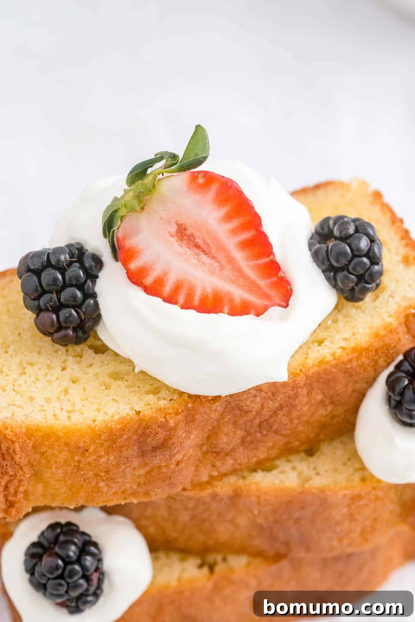 Timeless Pound Cake Perfection 14 A vibrant arrangement of pound cake slices, generously topped with fresh berries and whipped cream, creating an irresistible and colorful dessert display.