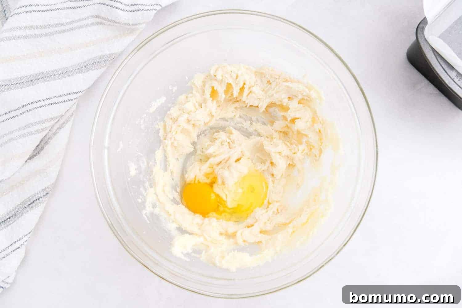 Timeless Pound Cake Perfection 7 A single egg is being added to the creamed butter and sugar mixture, ready to be beaten for thorough incorporation.