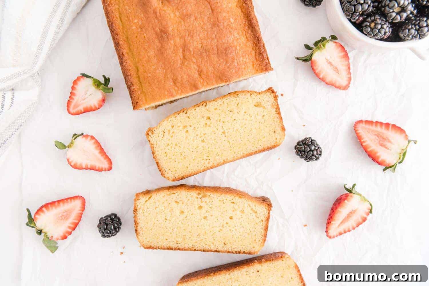 Timeless Pound Cake Perfection 10 A perfectly baked, golden-brown pound cake, freshly sliced, with vibrant fresh strawberries scattered around, ready to be served.